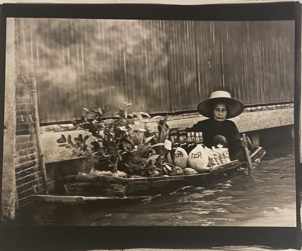 A woman in a boat with many vegetables.